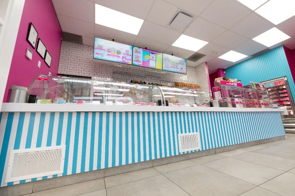 Blue-and-white striped service counter beneath digital menu screens — POKO POPCORN — SURREY, BC