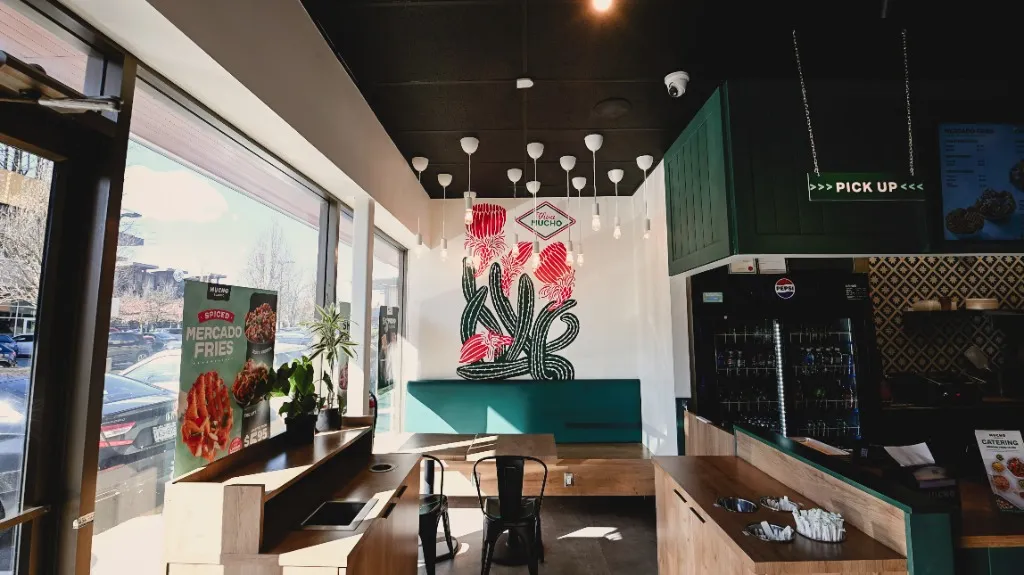 Window-side dining area with booth seating and a floral wall mural — MUCHO BURRITO — SURREY, BC